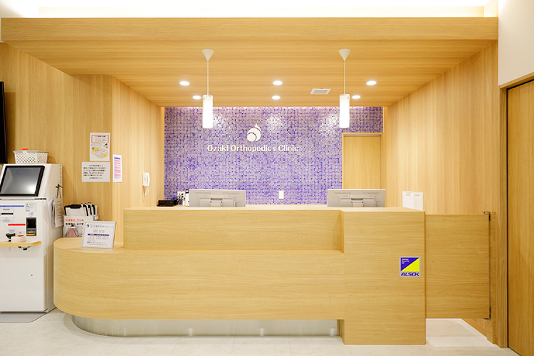 おざき整形外科クリニック 松原市 木目調の受付では、笑顔でスタッフが迎えてくれる