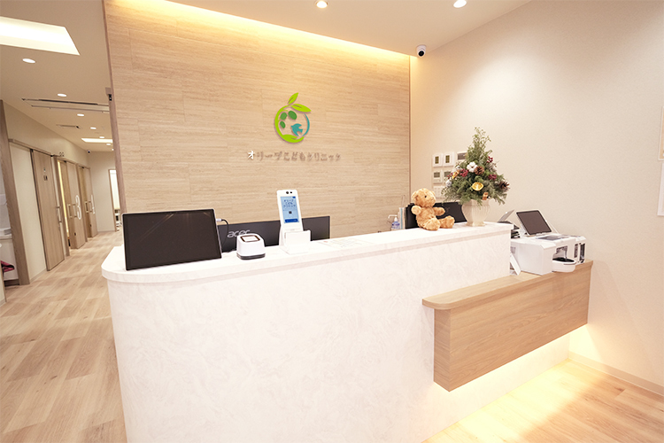 オリーブこどもクリニック 大阪市中央区 木目調で温かい雰囲気の受付では、スタッフが笑顔で出迎える