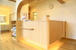 五月町デンタルクリニック 新潟市江南区 ウッドが多用された内装の受付。関節照明で足元を照らしている