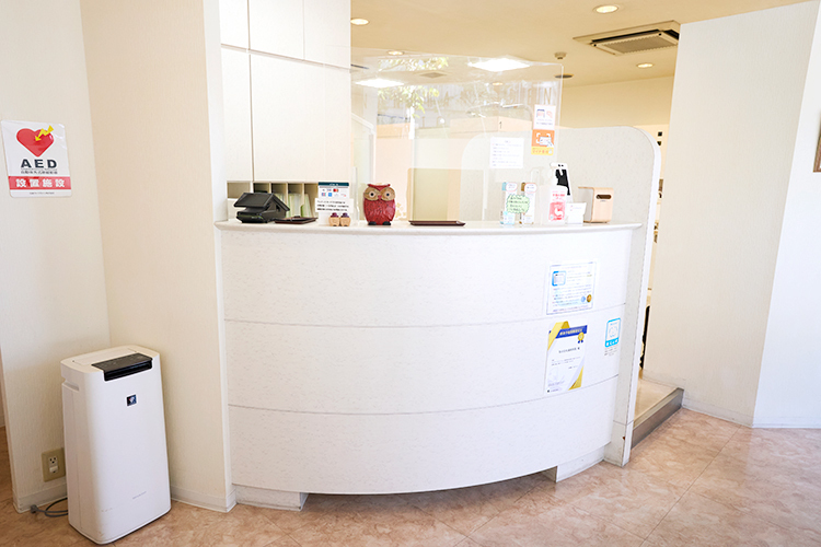 なのはな歯科医院 調布市 受付の壁には、保険診療・自費診療の一覧表を設置