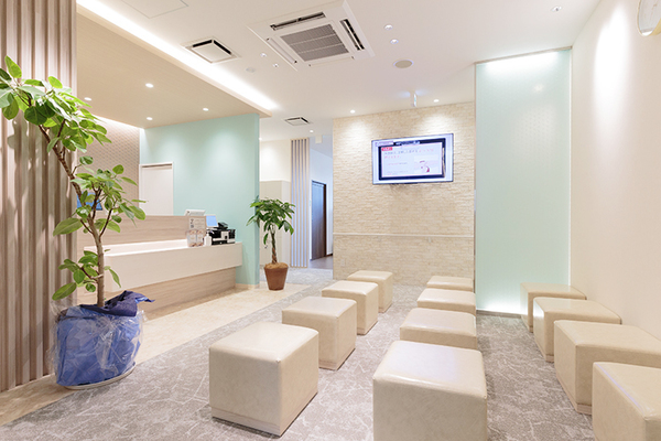 大阪なんば内科・消化器内視鏡クリニック 白を基調とした清潔感のある受付でスタッフが笑顔で出迎える
